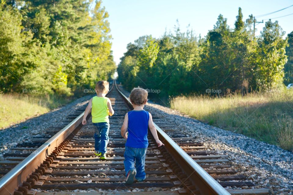 Our two grandsons walking on rail road having fun