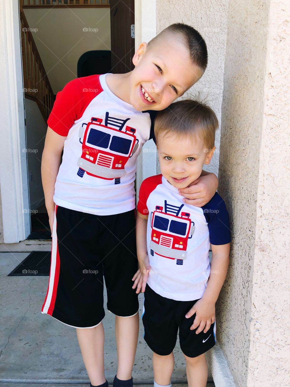 Two brothers wearing same shirts and hugging 