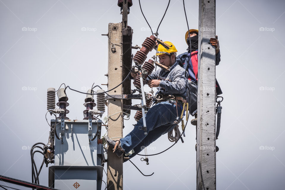 Electrician working together on the electricity pole to replace the electrical insulator