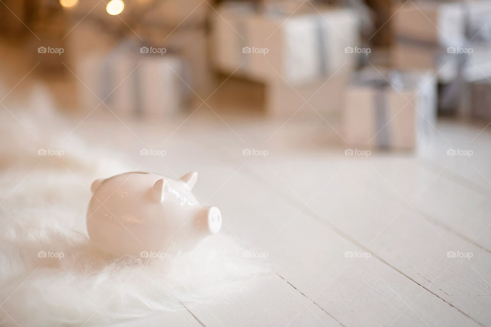 piggy bank with 100 dollars banknote in festive New Year atmosphere of scenery. Magical bokeh with Christmas tree and bright lights.