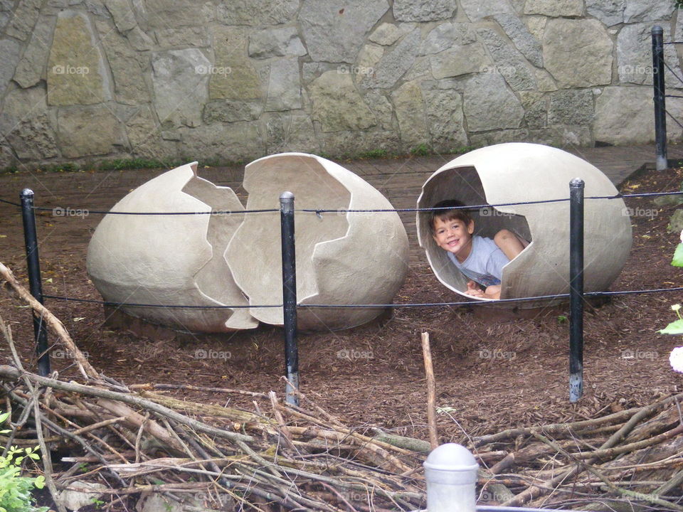 This boy is inside a pretend cracked open egg shell.