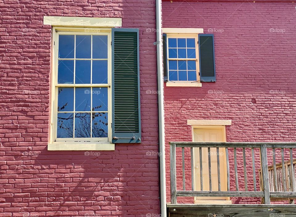 Two windows and a door in a red painted old farmhouse 