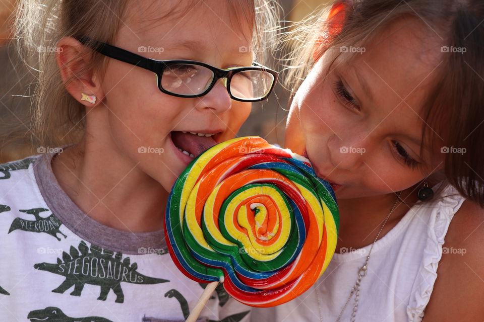 Two children sharing a lollipop