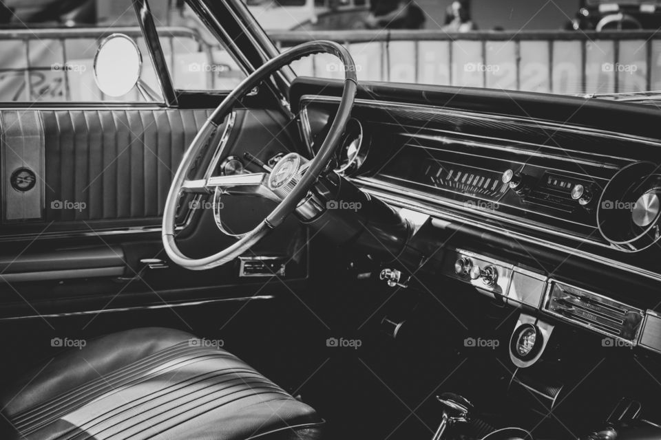 A black and white portrait of the dashboard and the rest of the interior of an oldtimer car. every detail is visible.