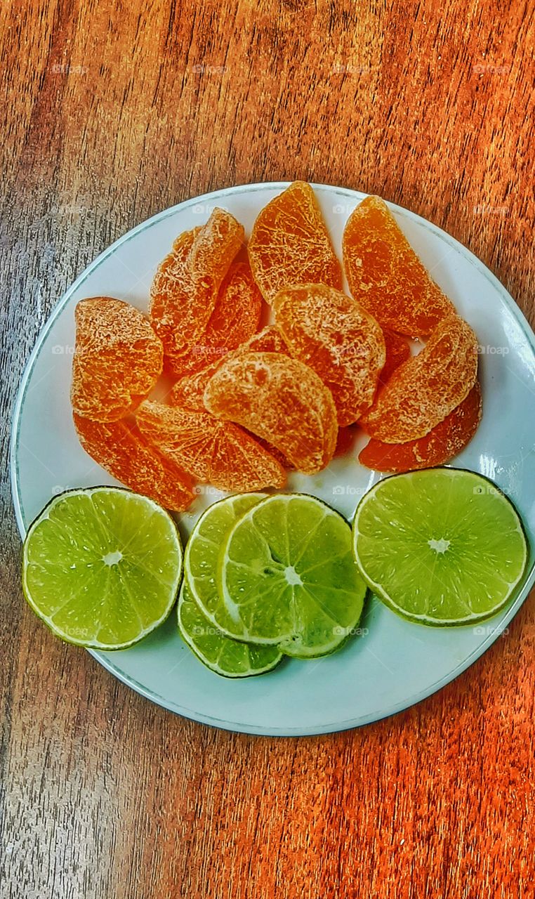дольки мандарина и лайма на белой тарелочке