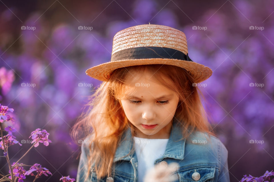 Cute little girl portrait in blossom meadow at sunset 