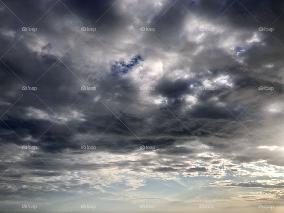 Storm clouds near while skies clear along horizon 