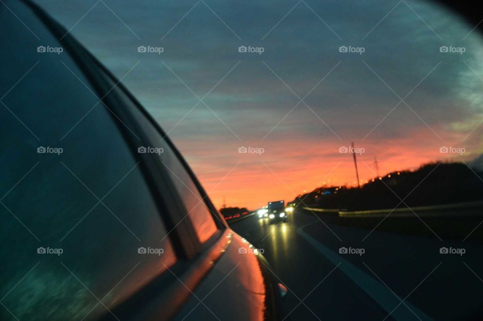 Colorful sunrise in the wing mirror in Alfa Romeo 159 car on the expressway in Poland