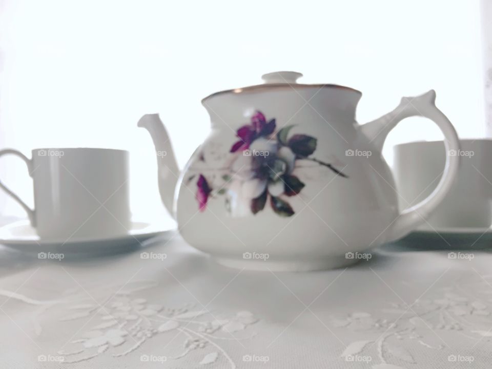 Tea Time - white porcelain teapot with painted burgundy and white wild roses, white teacups, on white tablecloth