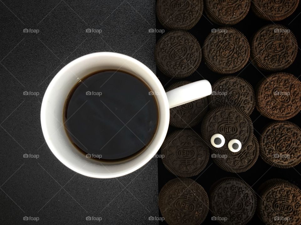 Oreo Original Chocolate Biscuits Flatlay with monster highly eyes and a white cup containing coffee.