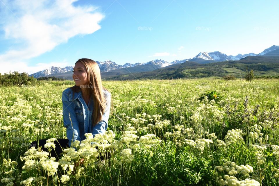 Young woman in a field of flowers with mountain background 
