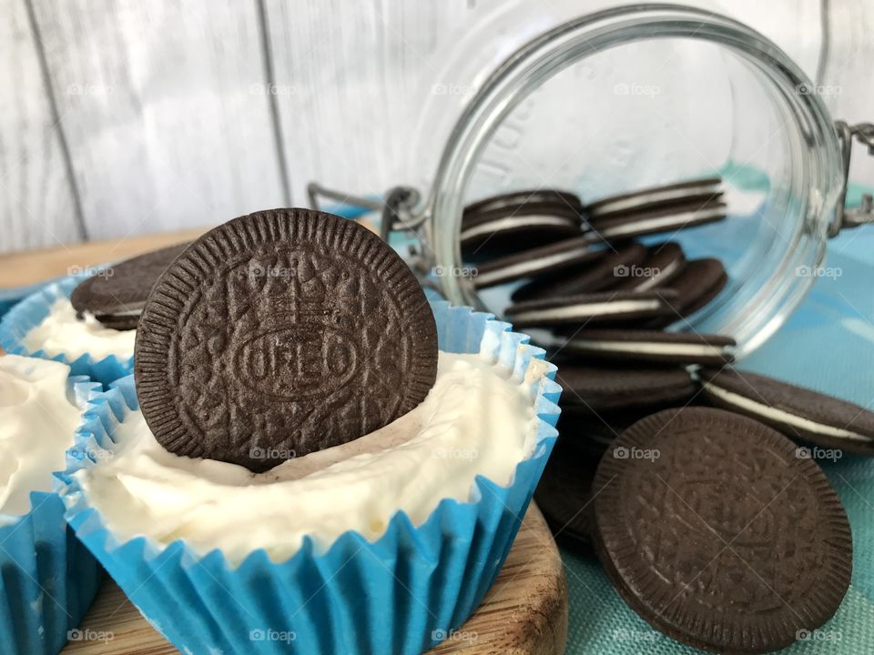 Oreo cookie ice cream cupcakes on a wooden board and white and blue background 