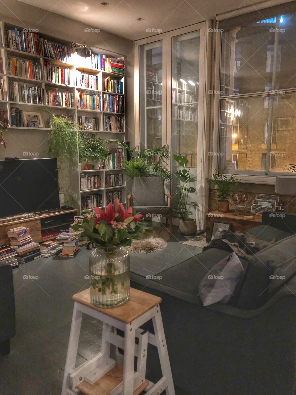 Cosy den in loft style apartment with bespoke bookshelves and gorgeous greenery