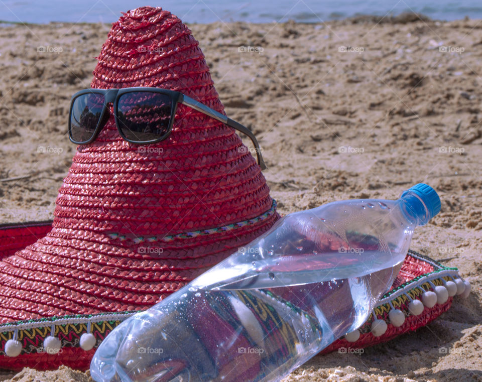 Hat of a sombrero and a bottle of drinking water lies on the beach