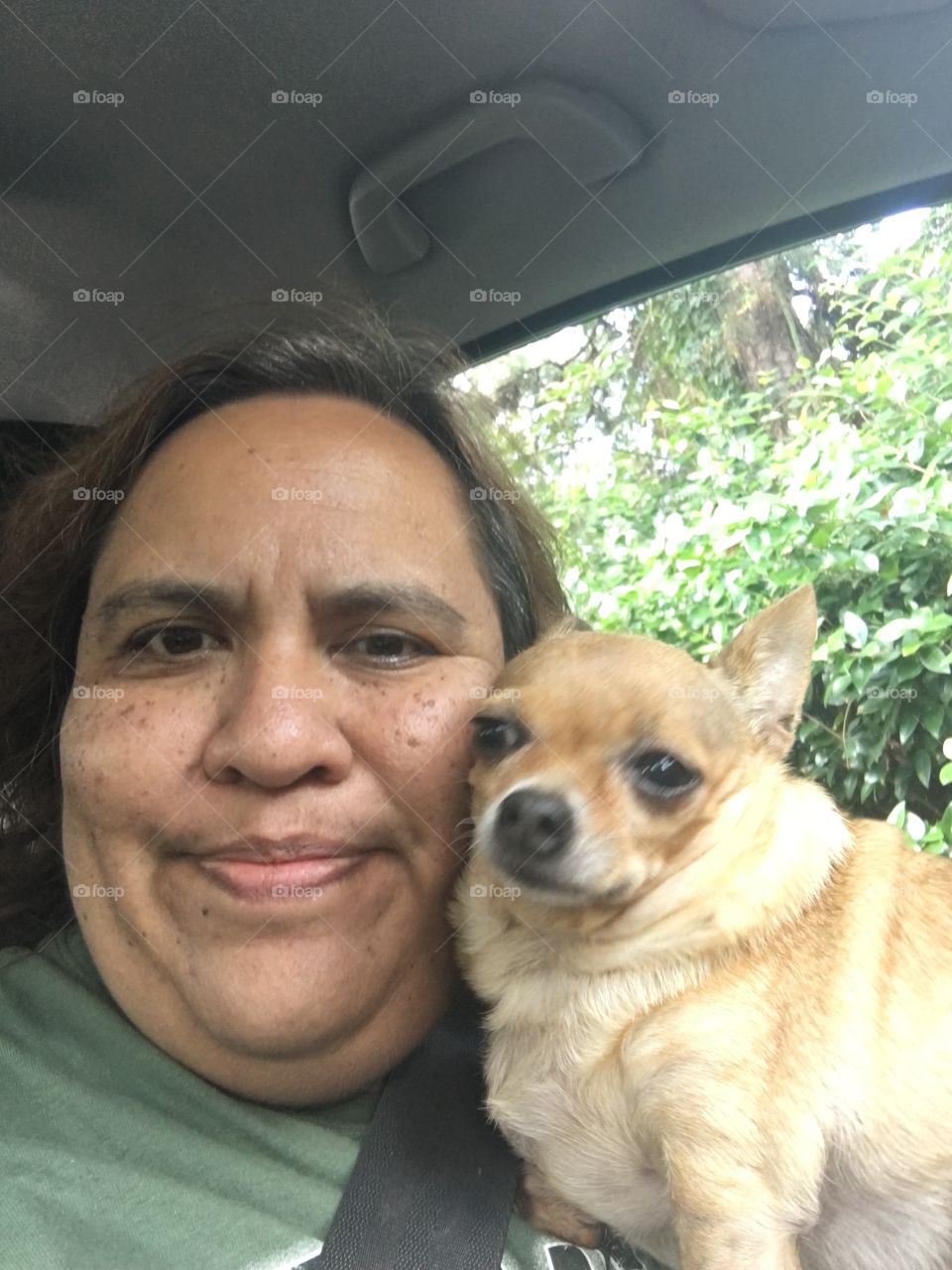 Mature woman holding pets dog in car