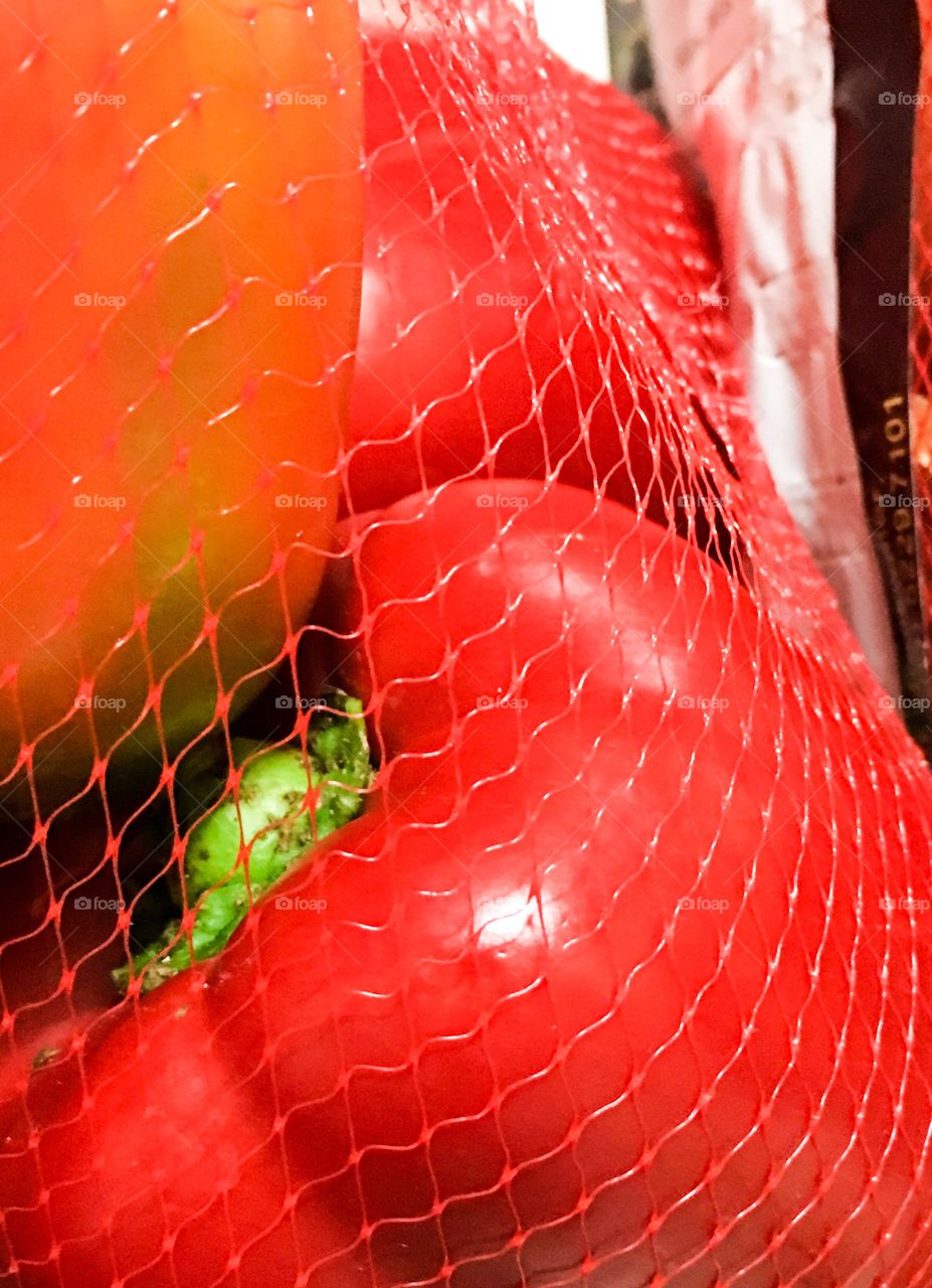 Sweet Red bell peppers capsicum in nylon mesh bag closeup bright vegetable background