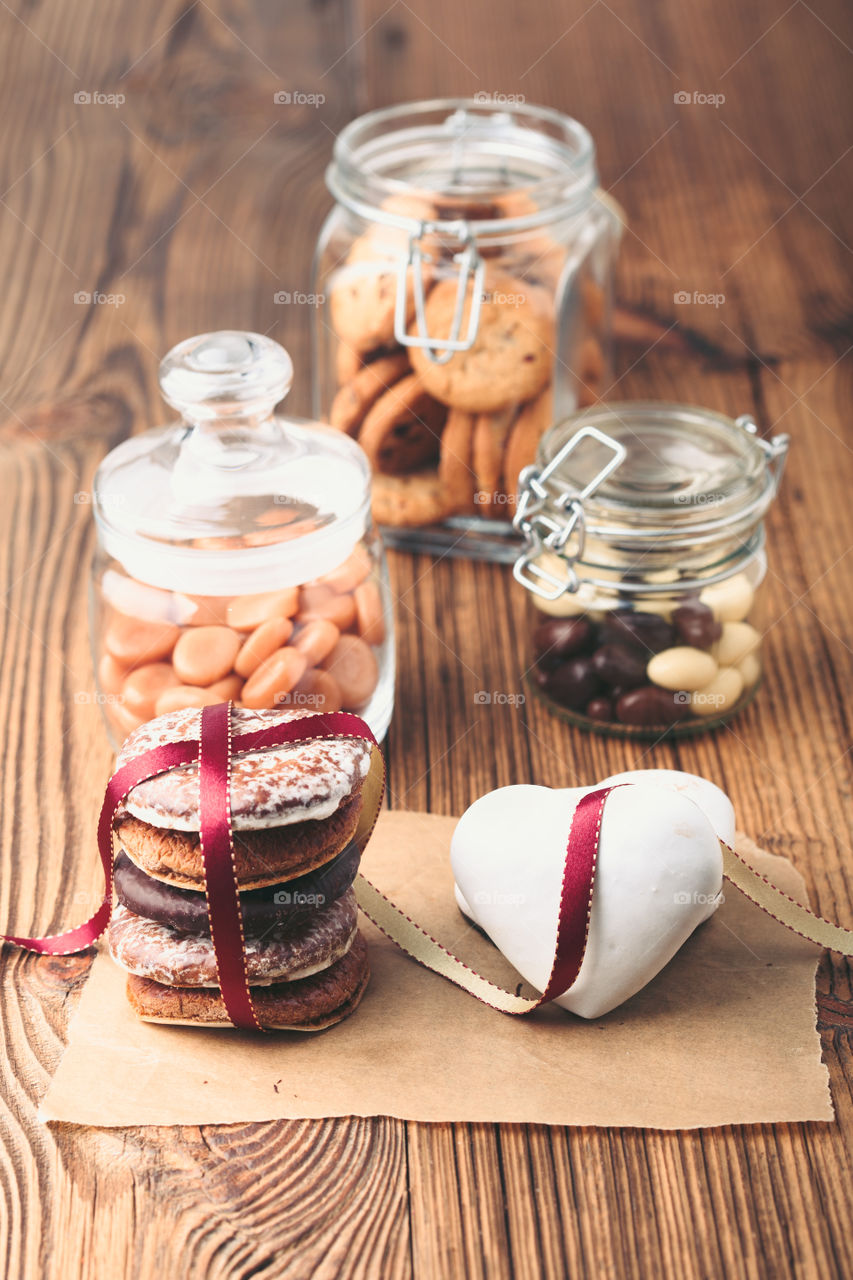 Gingerbread cookies, candies, cakes, sweets in jars on wooden table