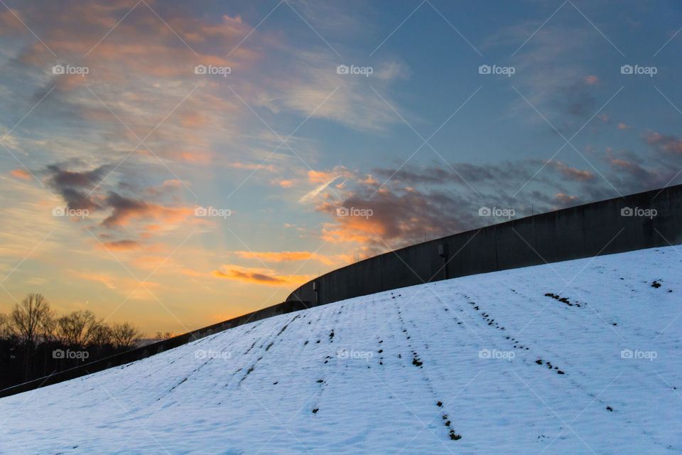 Gorgeous sunset over a snow covered hill with a building.