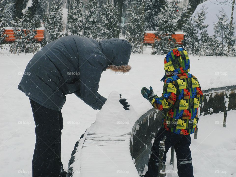 a man with a child makes a snowman