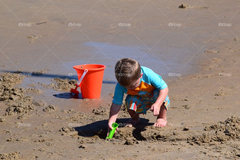 Beach Fun. A little boy digging in the sand at the beach.