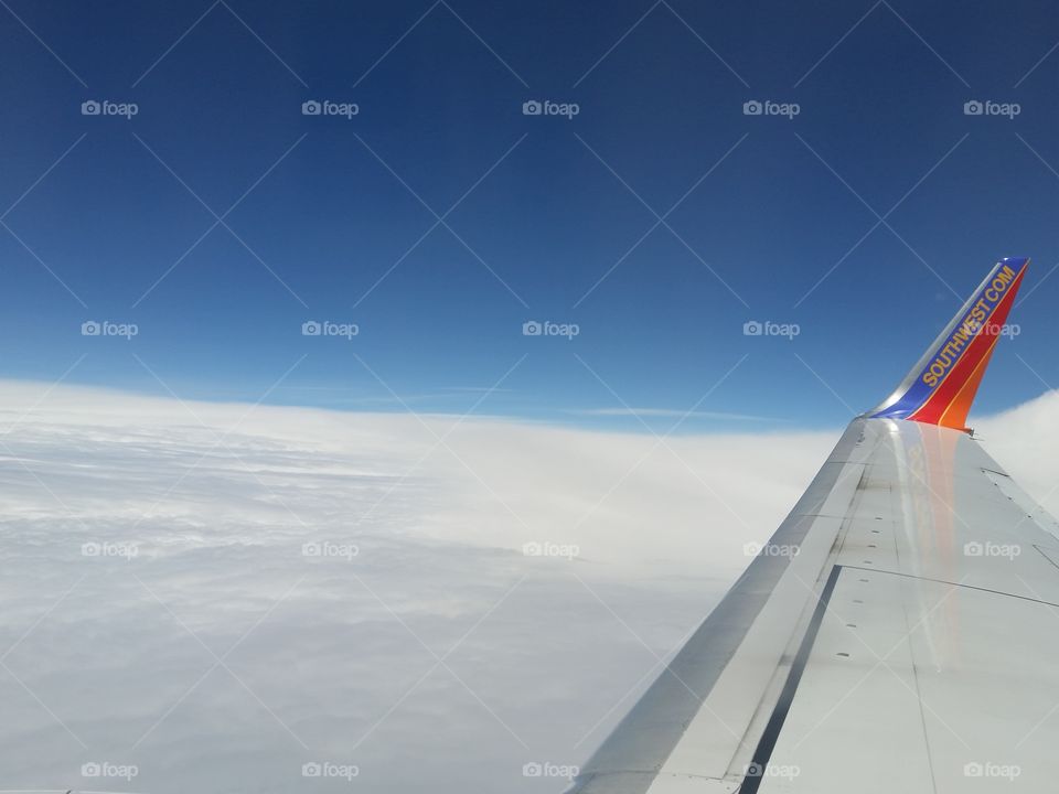 Airplane wing with clouds and blue sky