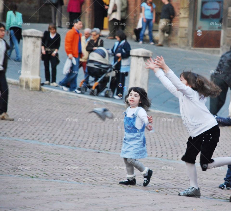 Exuberance. Little girls play in the village Square showing joy and exuberance