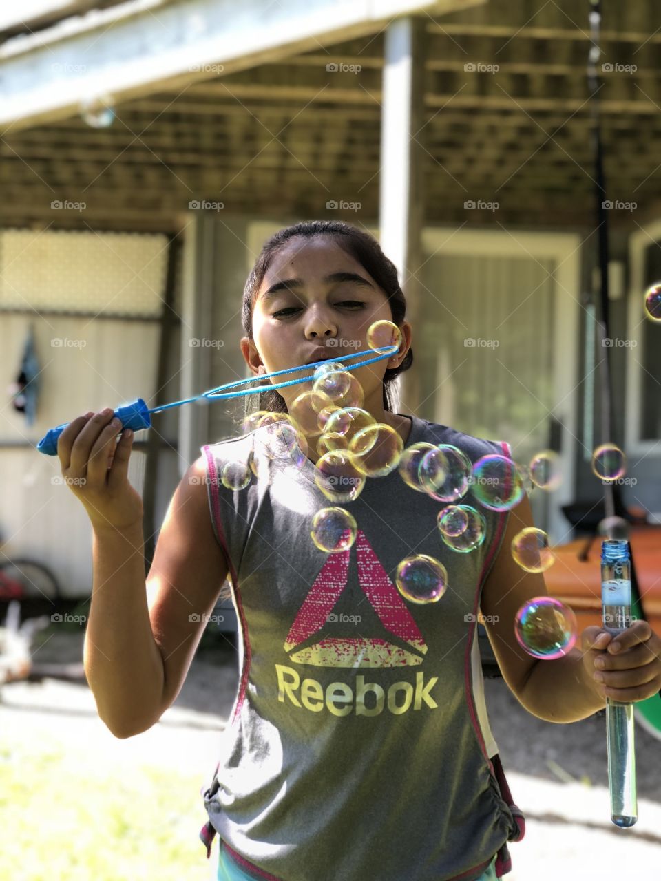 A girl blowing rainbow tinted bubbles outside on a beautiful sunny day. 
