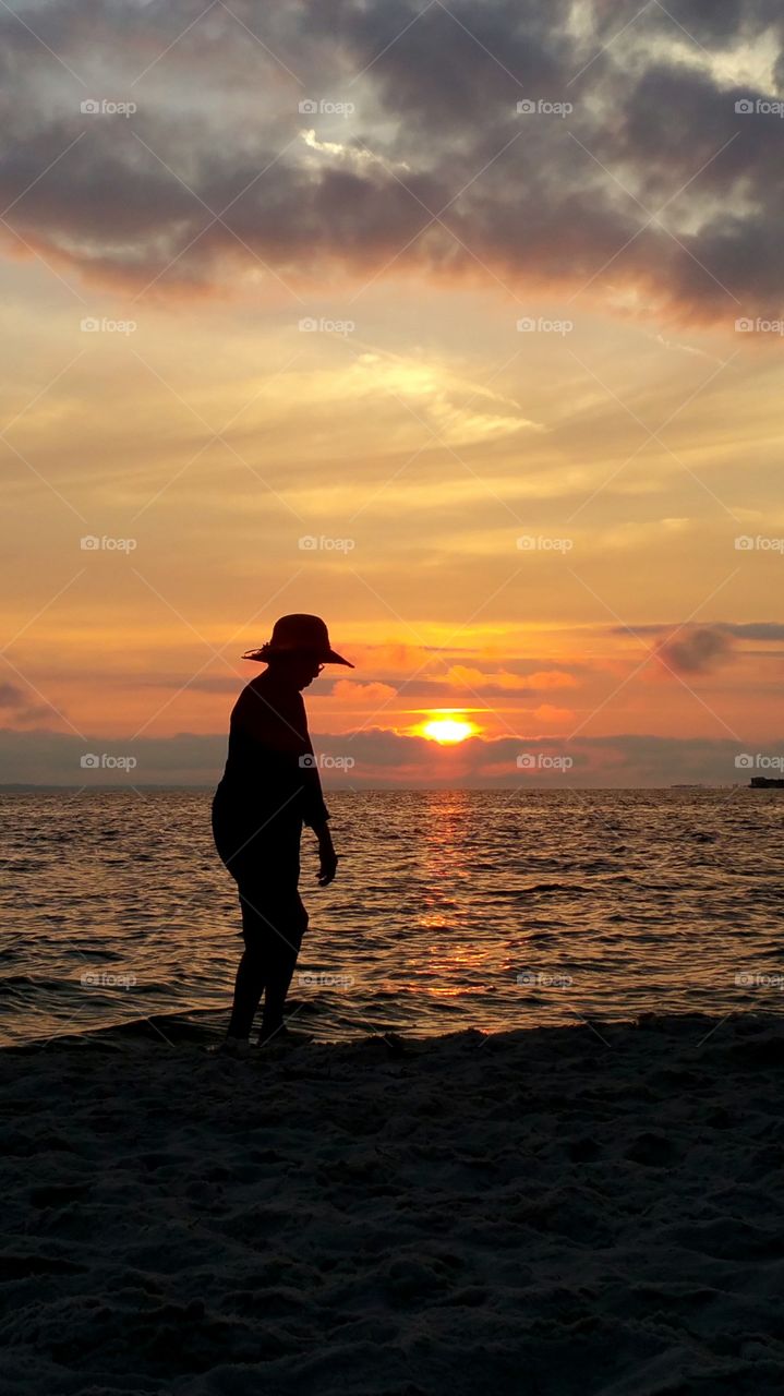 Silhouette of person standing at beach near sunset