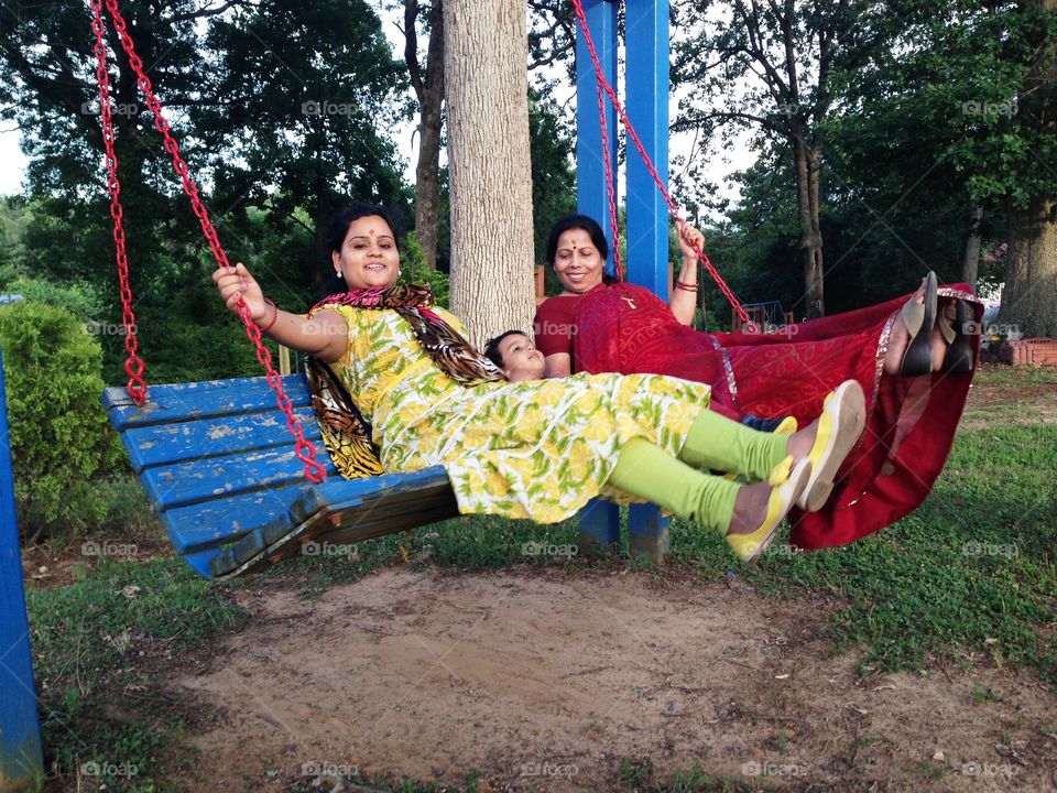 3 generation on a swing . Mom, mom's mom, and son. Swinging happy. Vibrant colors brilliant feelings. 