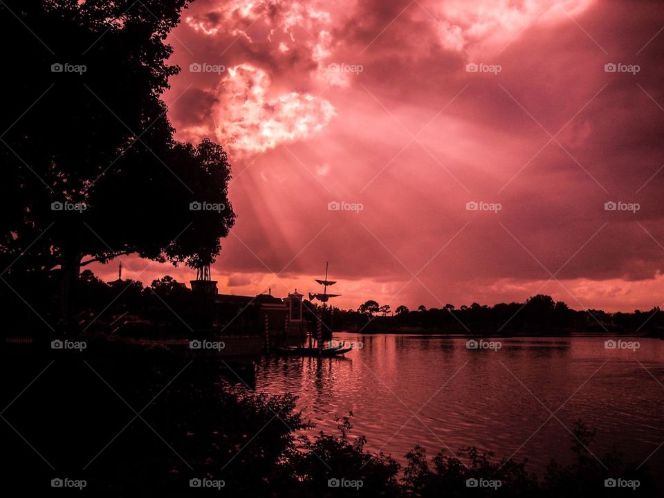 Dramatic sky over lake with silhouetted trees
