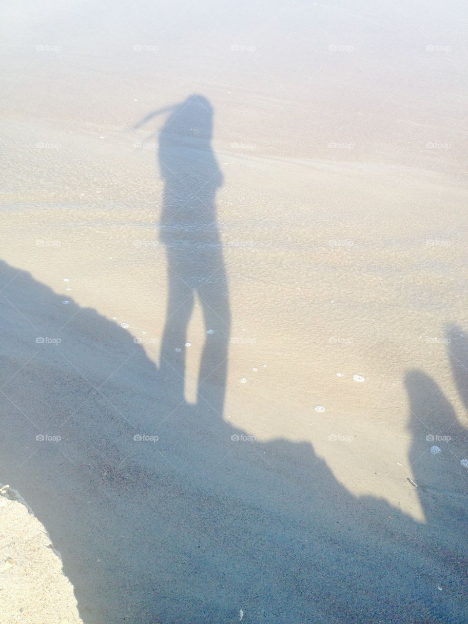 A shadow stands tall on the sands of a beach