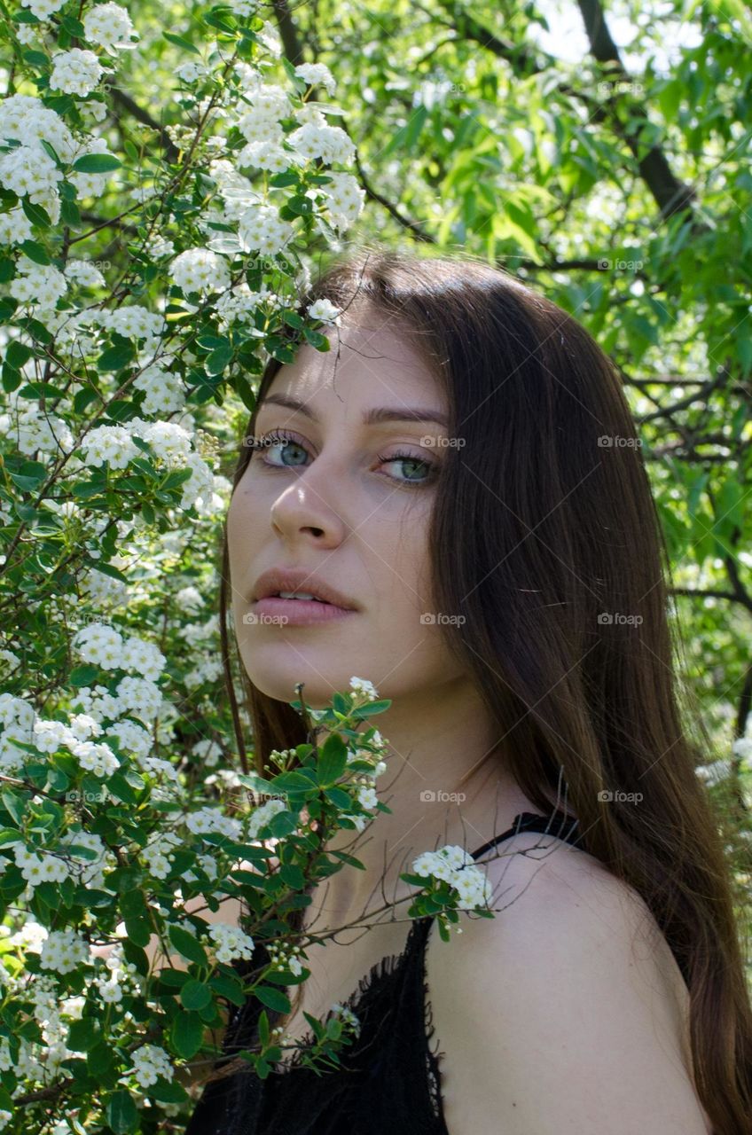 Portrait of Beautiful Young Girl on Background of Flowers