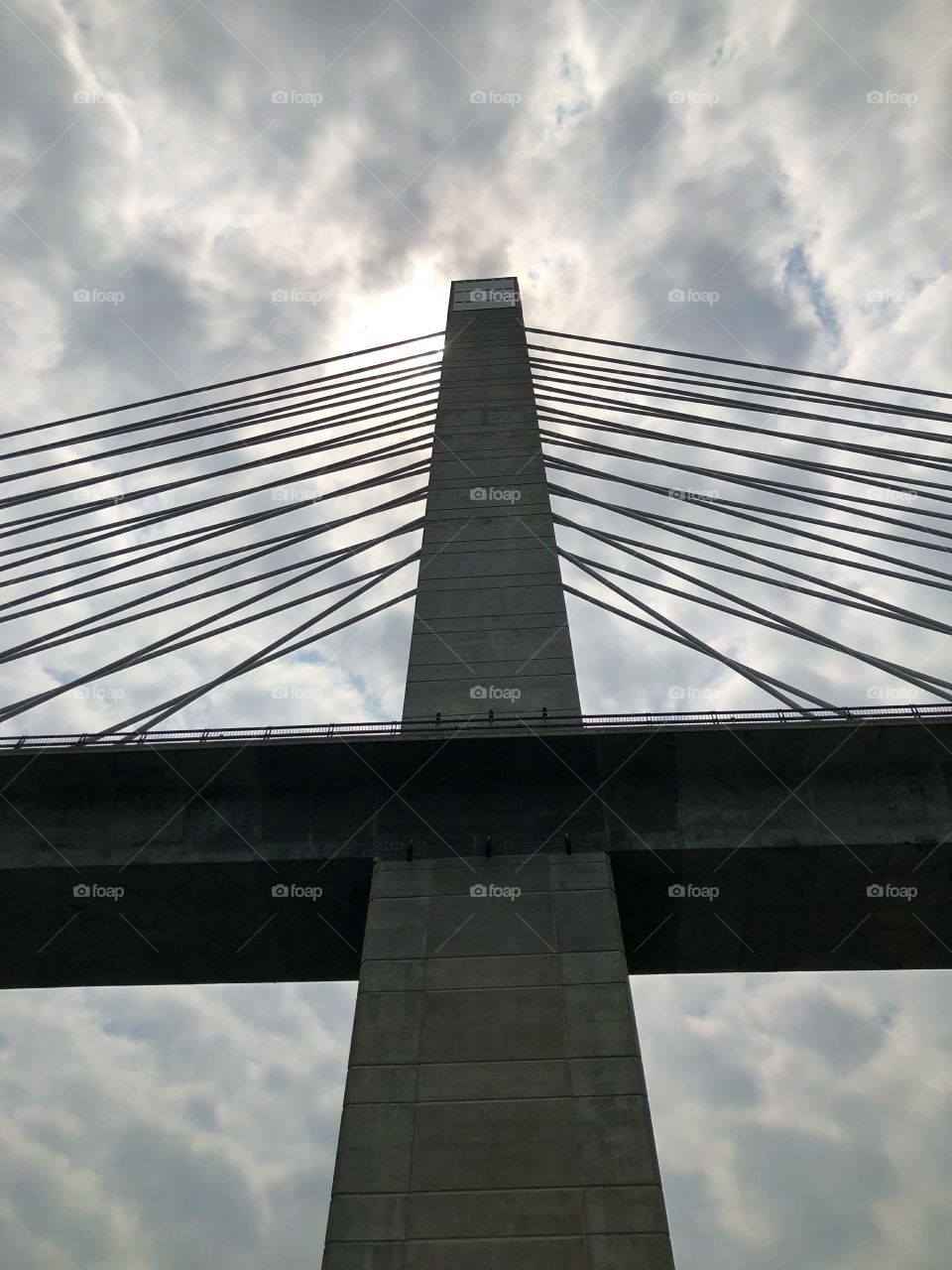 View from the ground looking up at Penobscot Bridge with cloudy sky in background