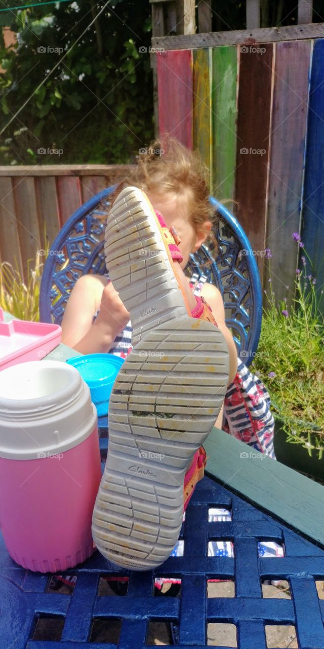 little girl with feet up on table outside in sumshine