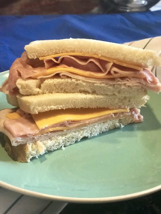 A ham and cheddar cheese sandwich on white bread on a plate served for lunch. USA, America