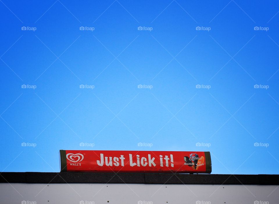 A red sign against a blue background saying 'just lick it'.