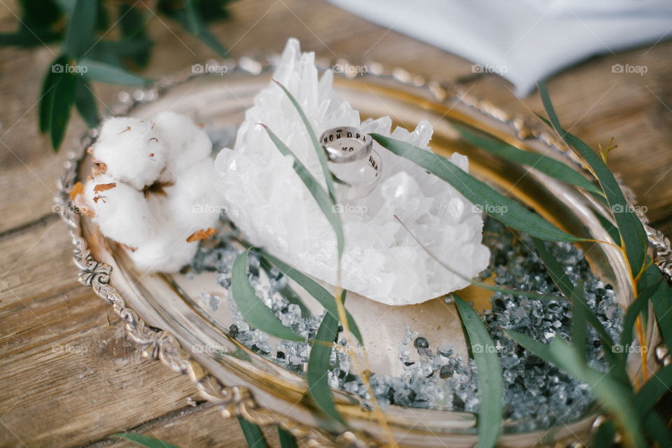 Silver plate with two wedding ring and white crystal on wood background.