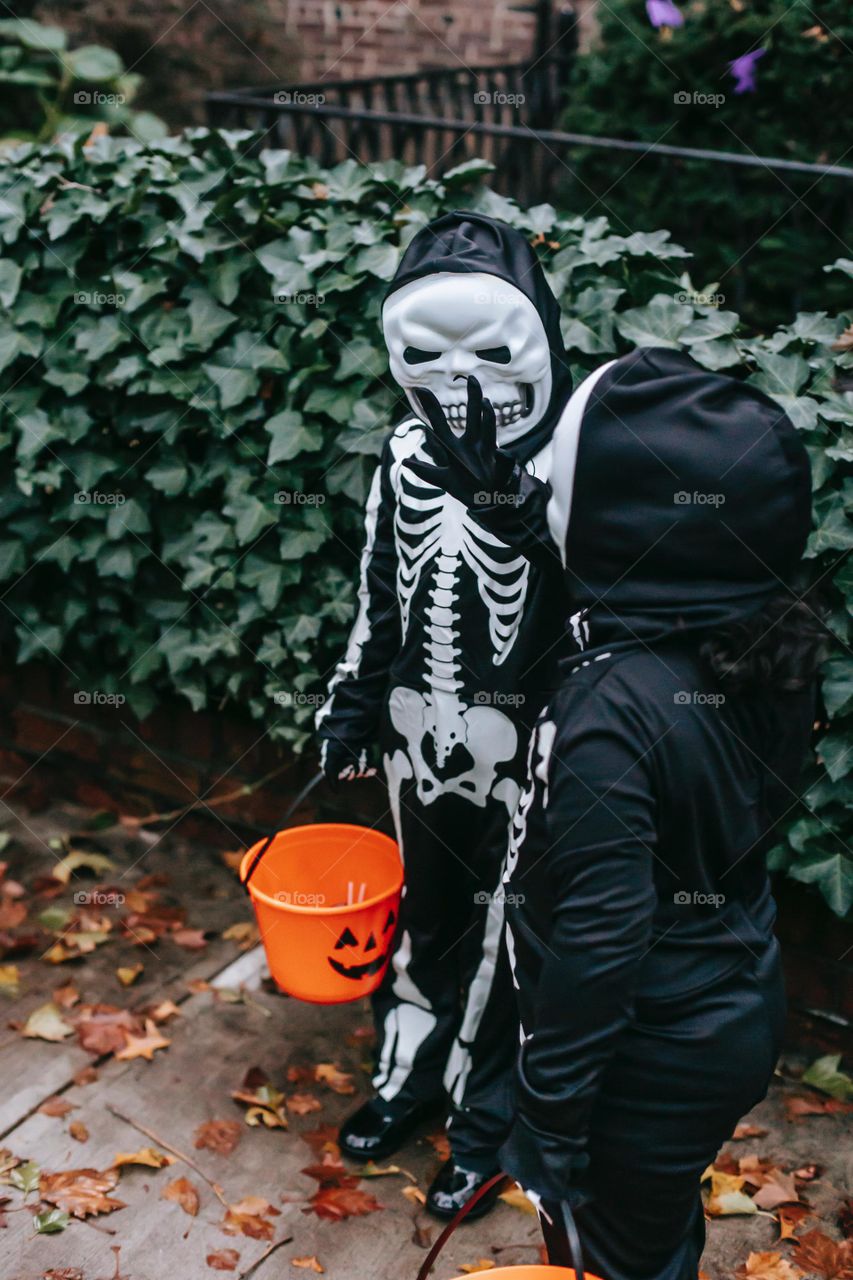 Anonymous children standing on sidewalk in Halloween costumes , orange and black 
