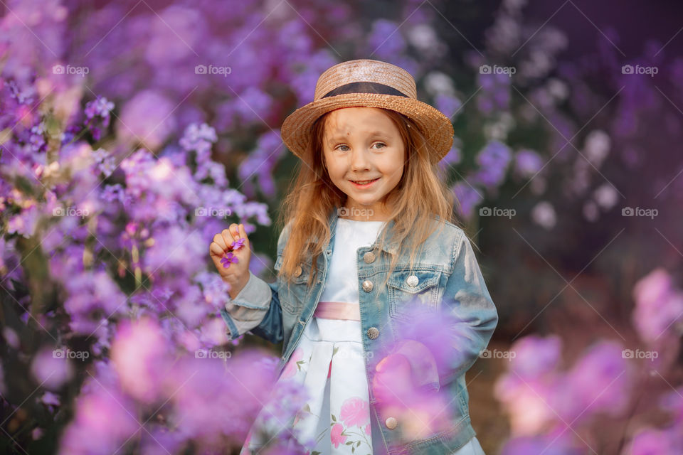 Cute little girl portrait in blossom meadow at sunset 