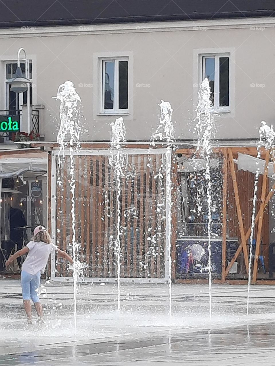 little girl among street fountains in summer