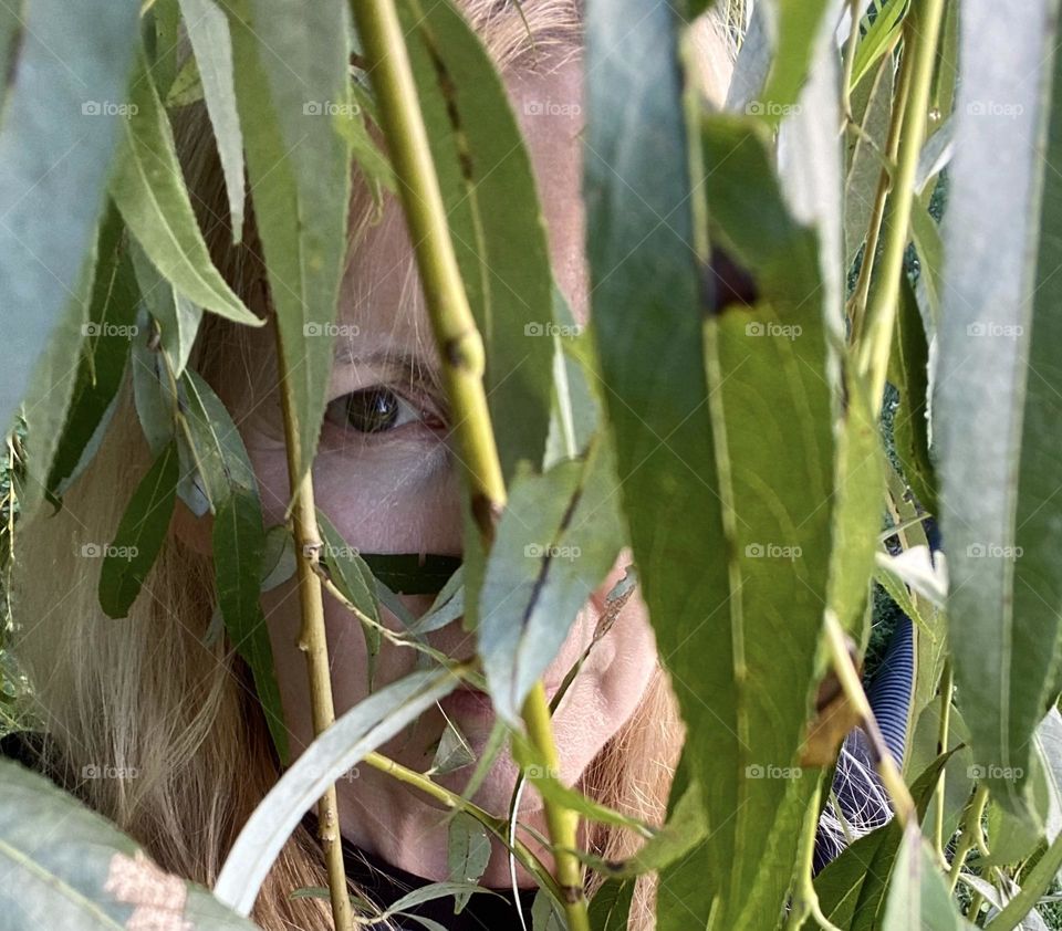 Woman looking through weeping willow branches