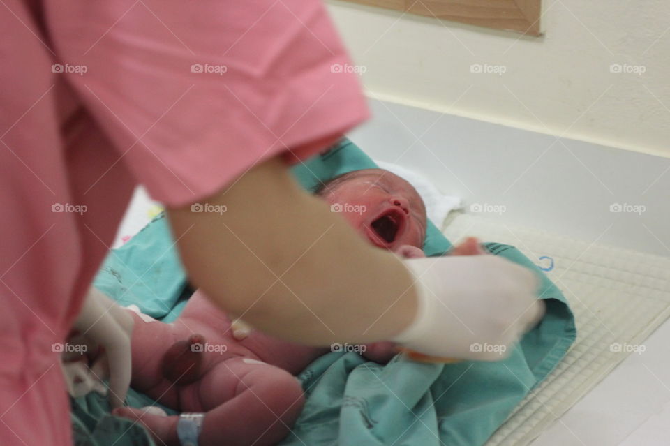 Newborn baby crying. nurse taking care of a newborn baby boy first bath