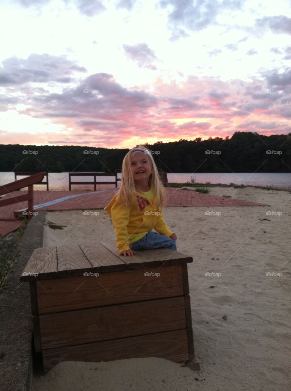 Girl admiring a beautiful sunset over lake.