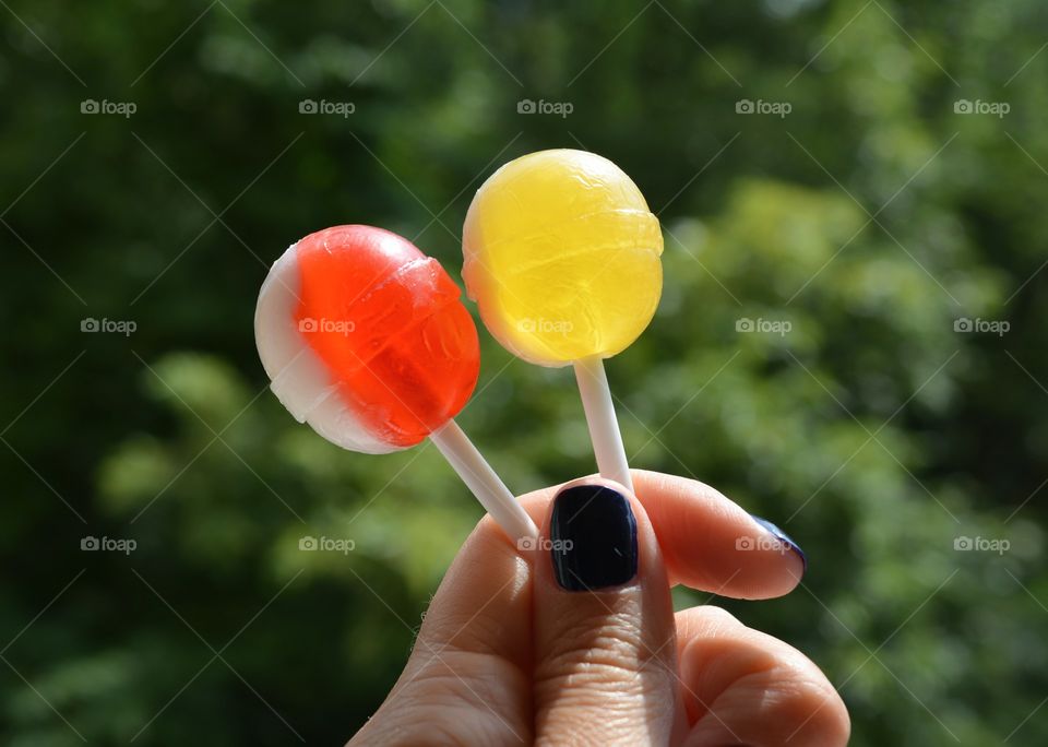 colorful candy lollipops in hand green summer background