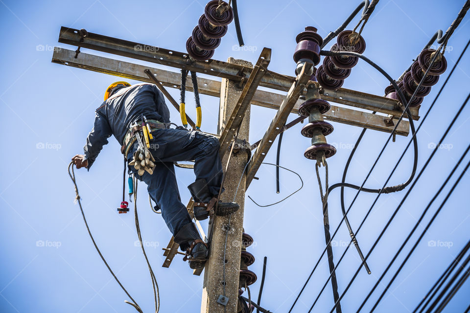 Electrician working on the electricity pole to replace the electrical insulator