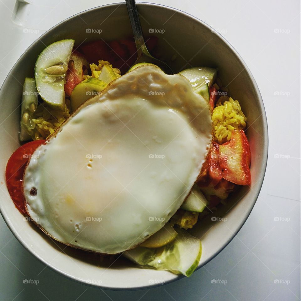 Food from the yard. Tomatoes, and cucumber over rice with a yard egg on top