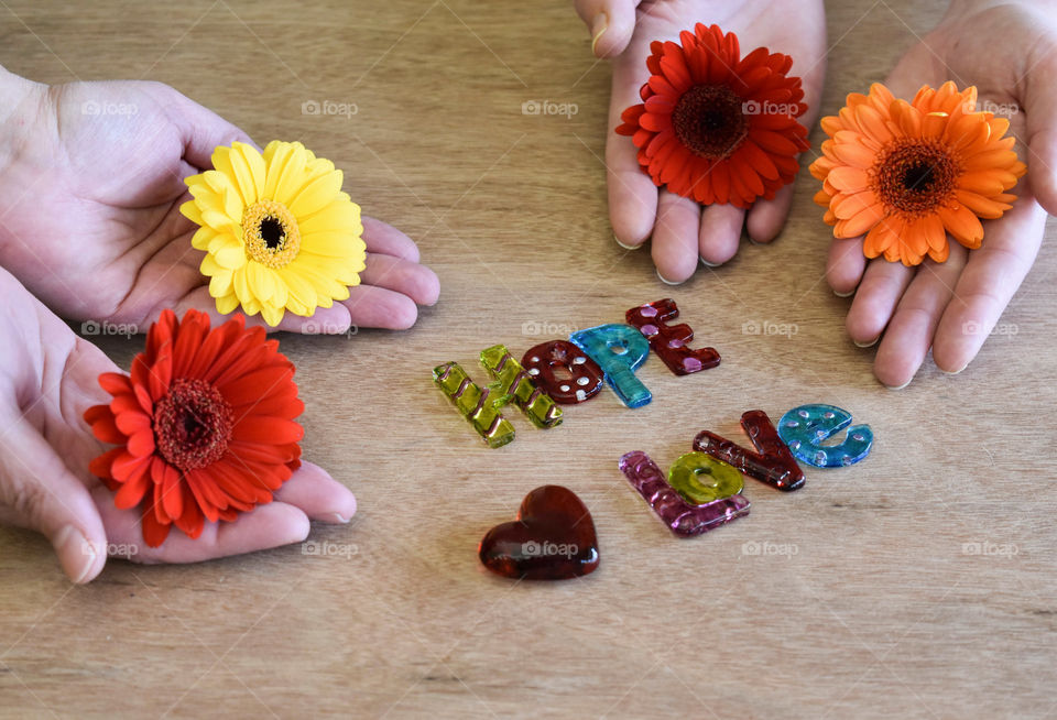 Set of hands holding flowers with art glass pieces spelling hope and love