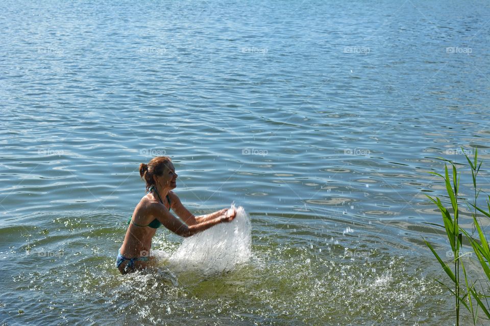 girl splash on a water lake shore summer heat, love water