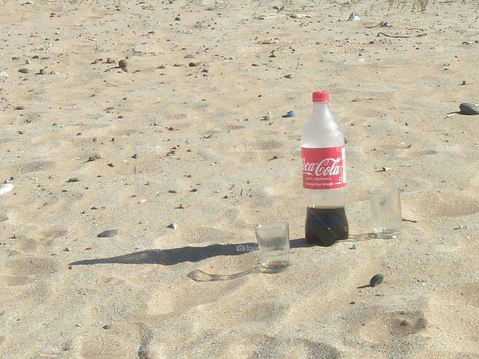 delicious bottle of fresh coca cola on sand.