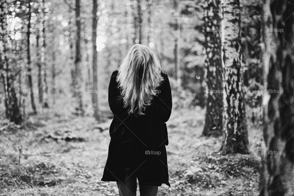 Man with long hair standing in the woods 